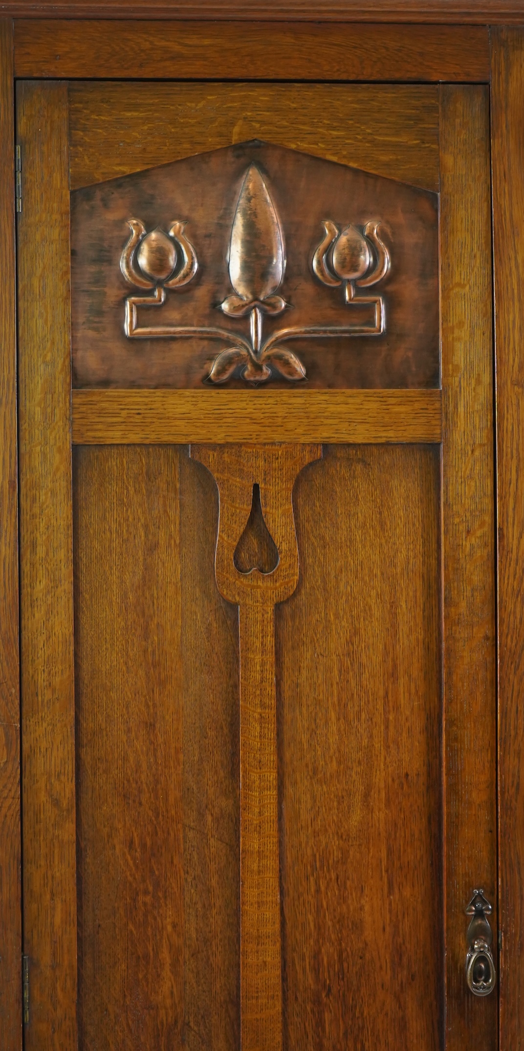 Manner of Liberty & Co: An Arts and Crafts embossed copper mounted oak hall cupboard